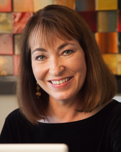 Rachel Dacus Author image. warm smile, wearing a black top with a brown shoulder length bob