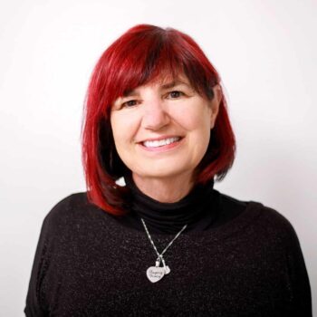 author photo Gail Taylor Black sweater silver necklace, red hair