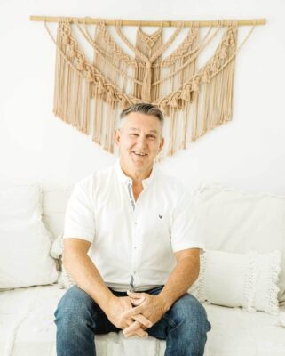 The Pyjama Boy by Steven Murphy | Memoir of Resilience & Survival 12 Steven Murphy seated in front of a white wall with a macramé hanging in the background