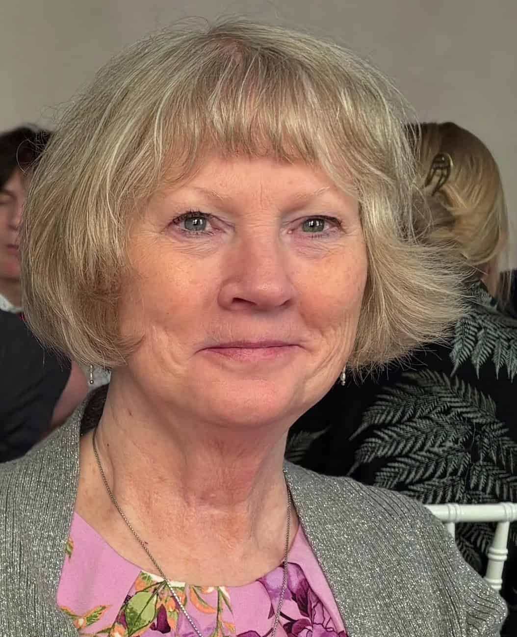 Author Lynn Crandall smiling at the camera, wearing a floral top and silver sweater, with a soft-focus background.