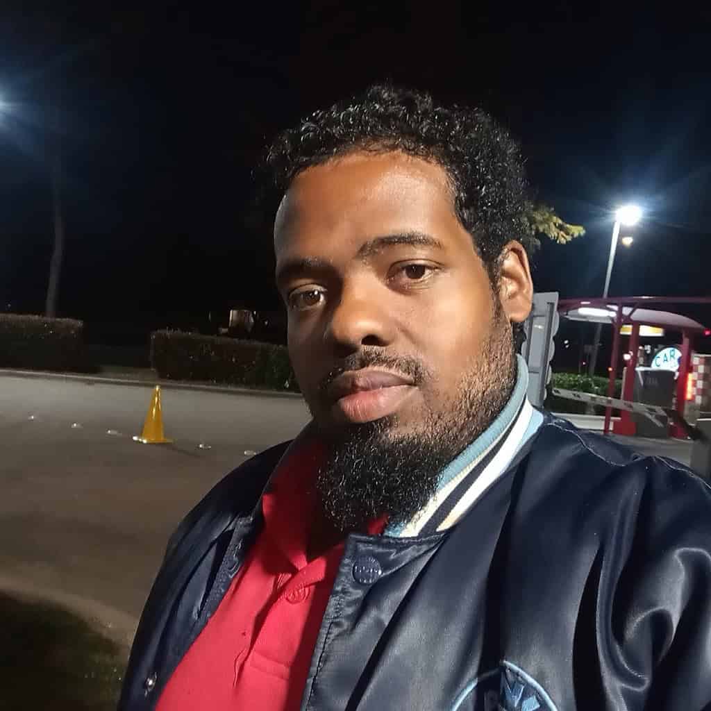 Poems of Life by JoeCephas White 6 Author JoeCephas White at night, wearing a red shirt and dark jacket, standing outdoors with parking-lot lights in the background.