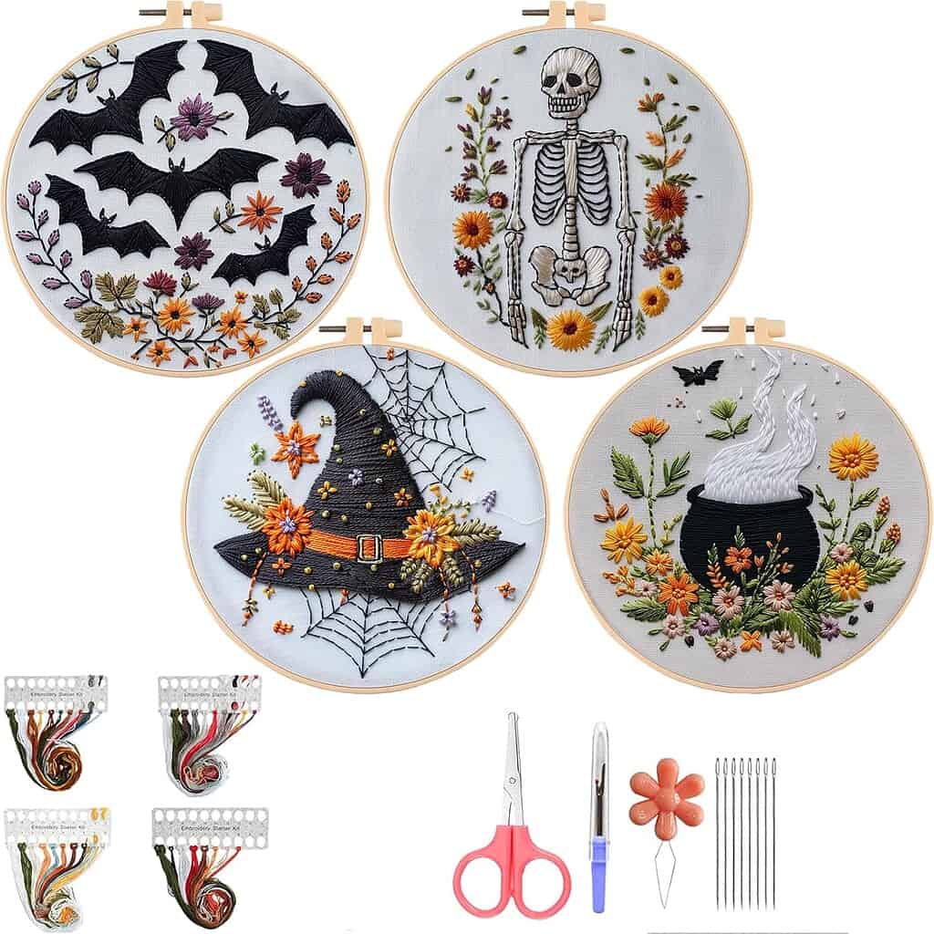 “Set of four Halloween-themed embroidery hoops featuring colorful hand-stitched designs: flying bats with autumn flowers, a skeleton surrounded by orange blossoms, a witch’s hat with spider webs and flowers, and a black cauldron with steam and blooms. Includes embroidery floss, scissors, needles, threader, and tools.”