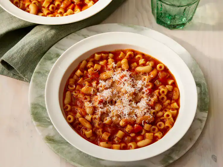 pasta fagioli served in a white bowl on a marbled green plate