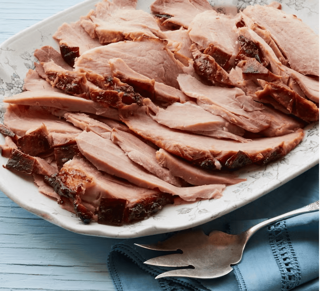 Root Beer-Glazed Ham served on a white seramic platter with an old-fasioned serving fork. recipe + image ©Pioneer Woman