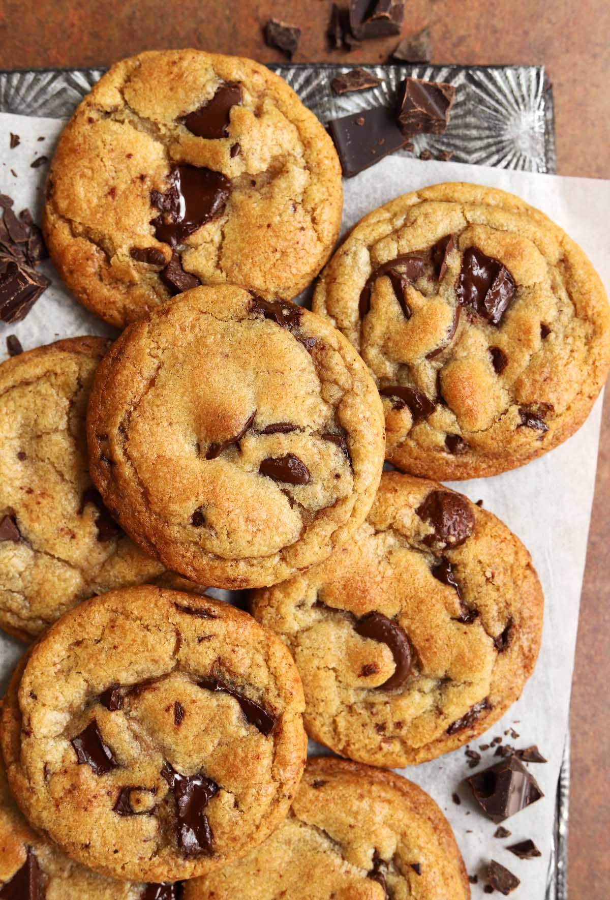 Brown butter chocolate chip cookies with crisp golden edges and gooey chocolate centers, photographed on parchment paper with chocolate chunks.