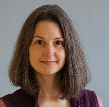Author portrait of K. Kris Loomis, showing her facing the camera with shoulder-length brown hair and a calm expression against a neutral background.