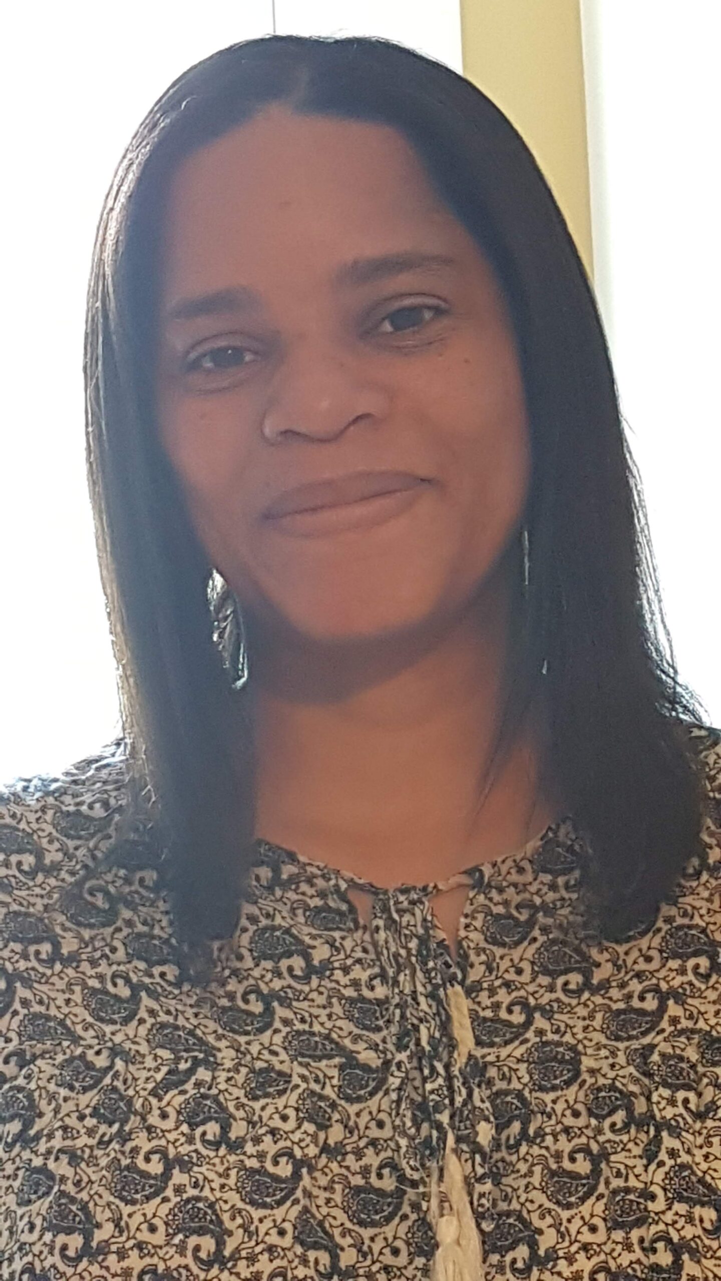 Author V.G. Harrison profile image with a closed-mouth smile, wearing a print top in an outdoor setting.