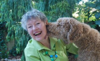 Author Debra Borchert smiling outdoors with her dog, featured in an author interview on GinaRaeMitchell.com.