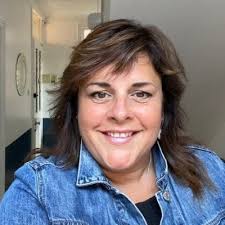 Author J. M. Simpson smiling in a casual headshot wearing a denim jacket, author of the romantic suspense novel Christmas in Castleby.