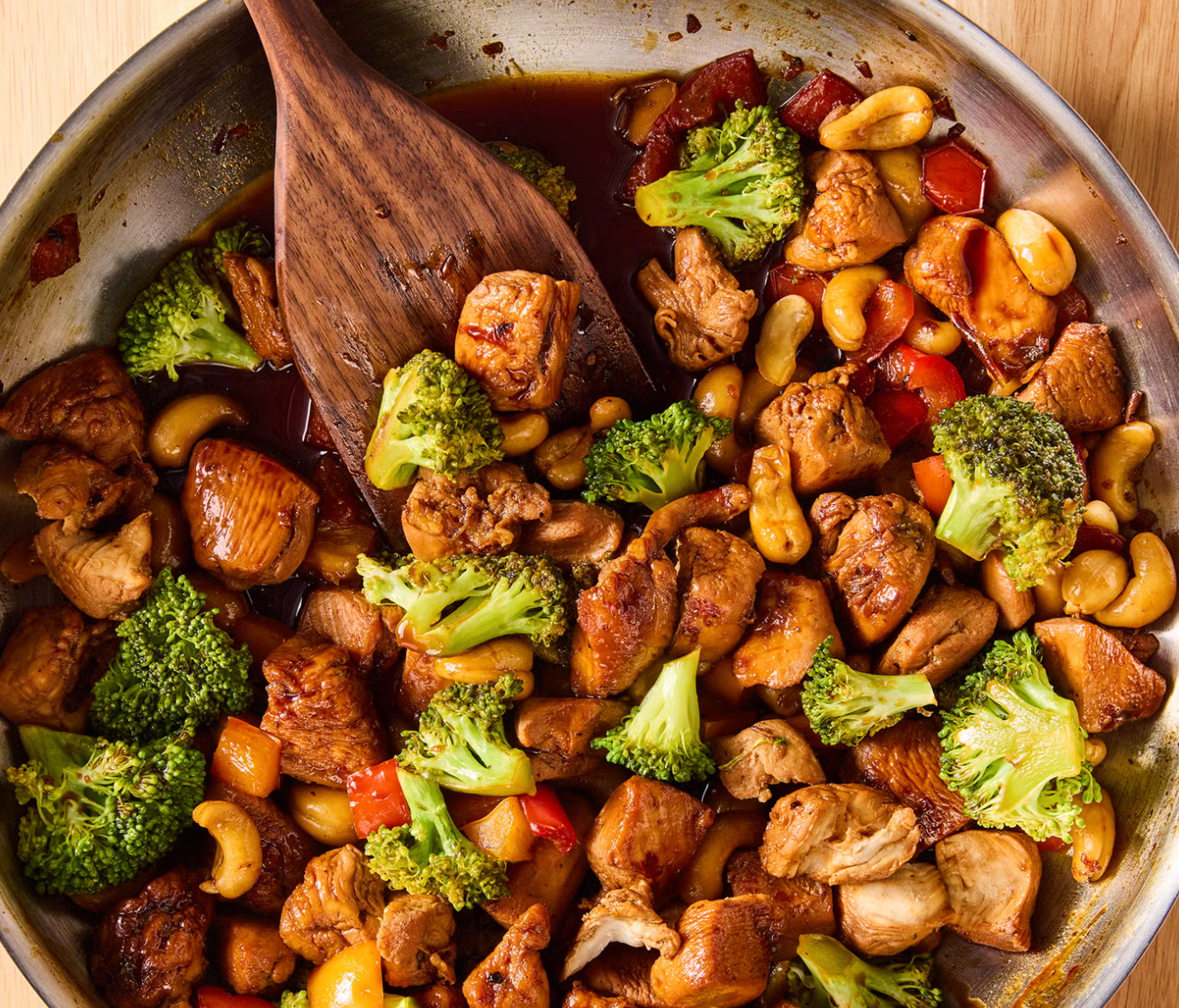 Chicken stir-fry in a skillet with a wooden paddle 