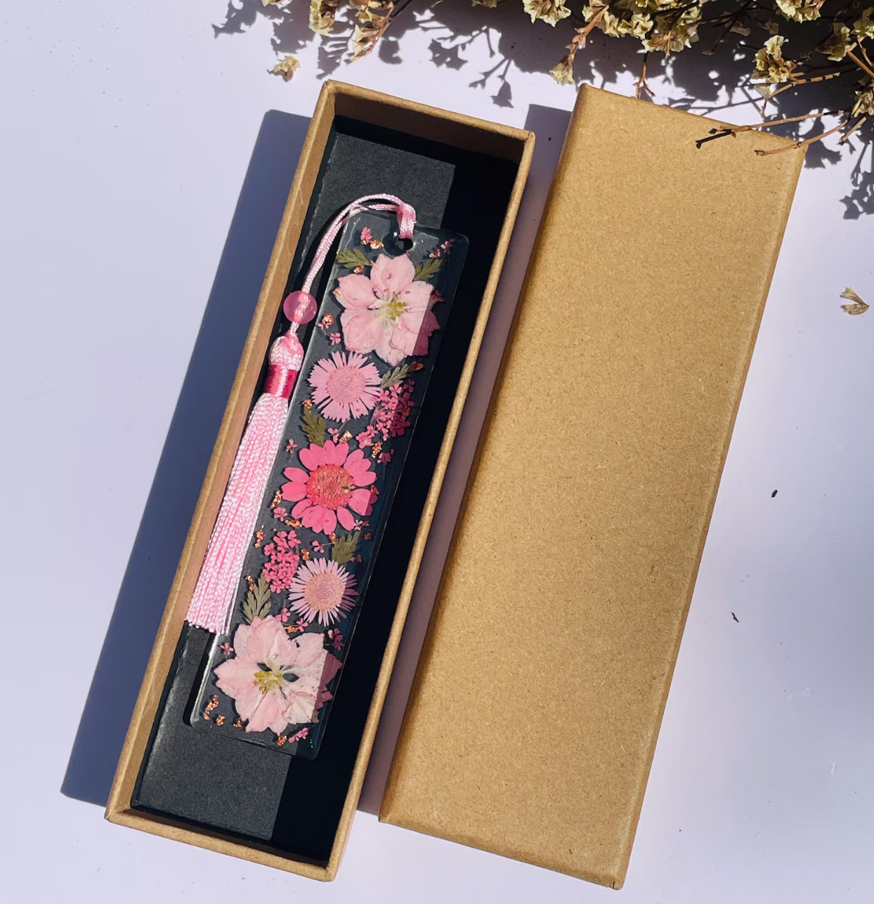 Handmade pressed flower resin bookmark in a gift box with soft pink floral design and tassel.