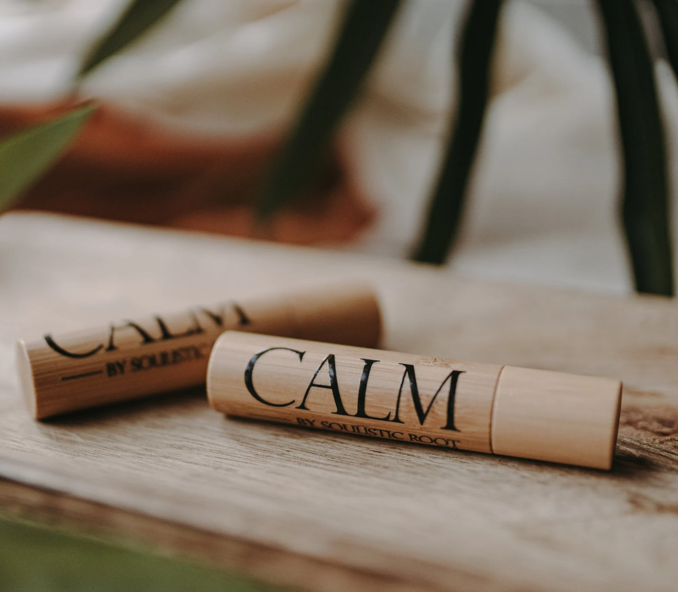 Calming essential oil roller in bamboo tube labeled calm, a portable self-care item for relaxation