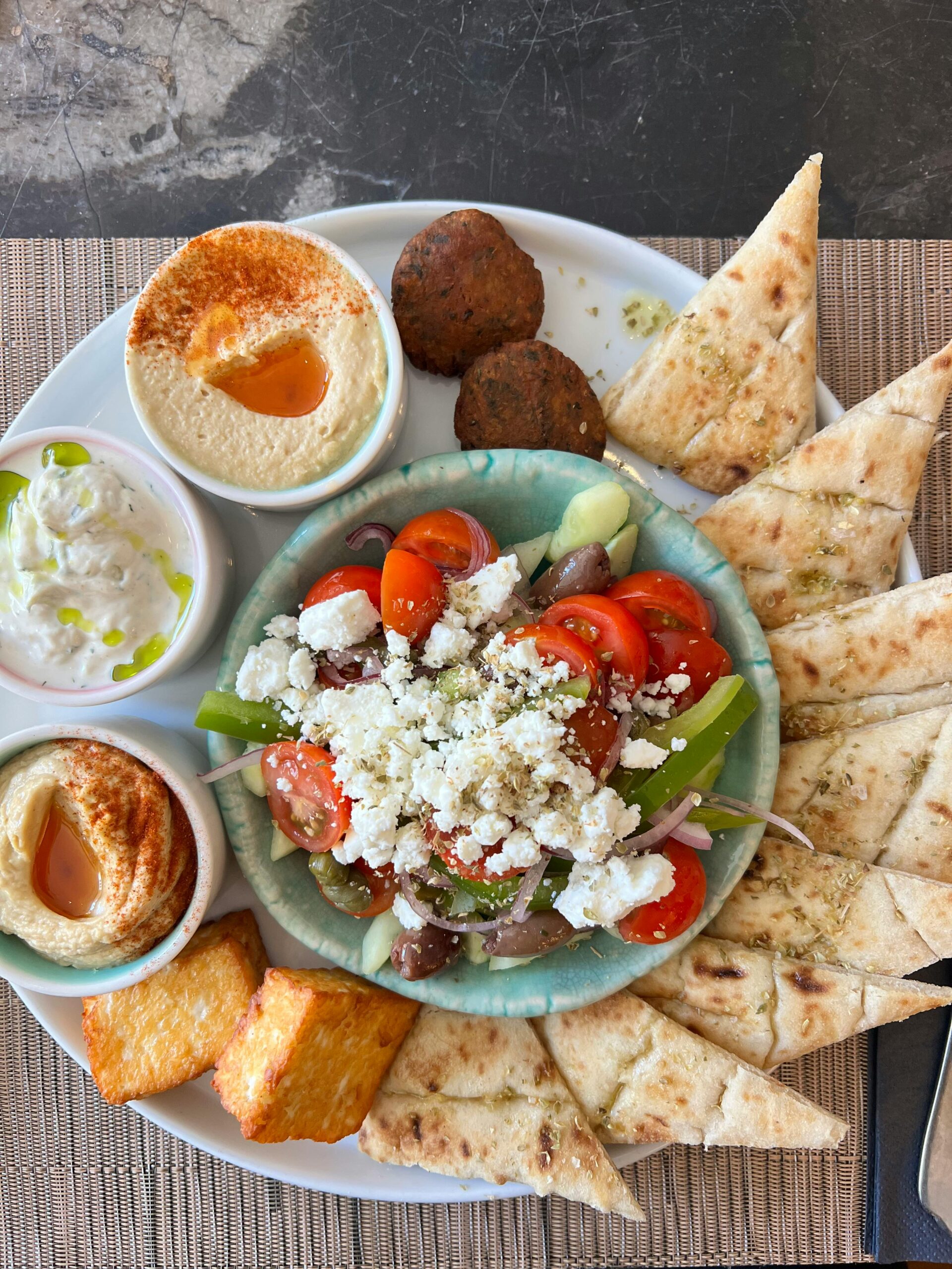 authentic Greek mezze platter with fresh vegetables, dips, and pita