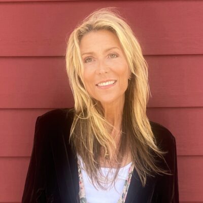 Author photo of Raven Howell, children's book author of Word Up, smiling against a red wooden background