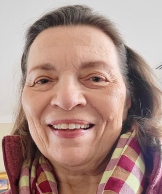 Headshot of Robin R. Cutler with hair pulled back & wearing a plaid scarf