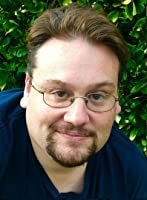 Author John Stovall smiling outdoors in front of green foliage.