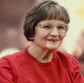 Author Pamela Gibson wearing glasses and a red sweater, smiling softly against a blurred neutral background.